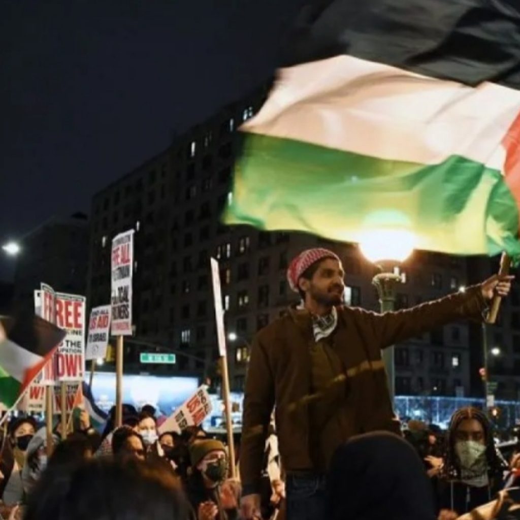 Seorang lelaki mengangkat bendera Palestina di sebuah demonstrasi pro-Palestina di luar kampus Universitas Columbia di New York, AS.